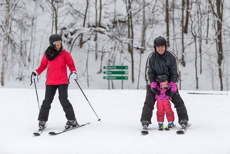 A woman skiing downhill next to a man helping a child ski downhill