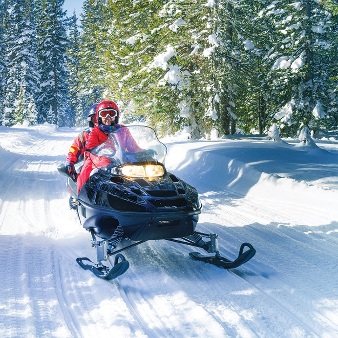 Two people riding a snowmobile on a trail at Muskoka Bay Resort